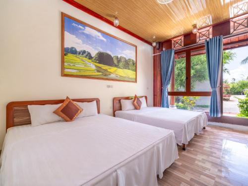 two beds in a room with two windows at Trang An Lighthouse Homestay in Ninh Binh