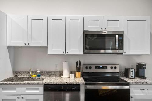 a kitchen with white cabinets and a black microwave at CozySuites Stunning 1BR in Downtown Pitts #12 in Pittsburgh