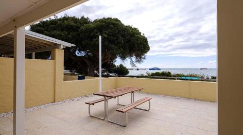 a picnic table and a bench in front of a wall at Stay Rottnest in Rottnest Island