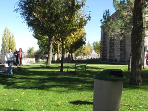 a trash can in a park with people walking in the grass at Hotel Restaurante Sonsoles in Avila