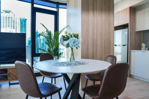 a dining room table with chairs and a vase of flowers at Sky-High CBD Living Walk to Everything in Sydney