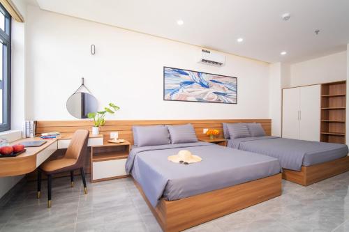 a bedroom with two beds and a desk and a deskablish at Binh An Motel in Da Nang