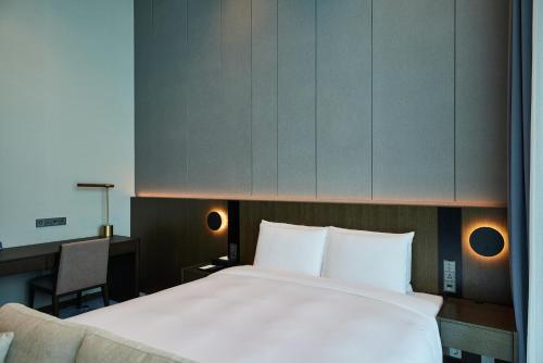 a bedroom with a large white bed and a desk at Hotel HLB in Busan