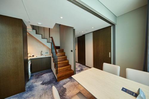 a dining room with a table and a staircase at Hotel HLB in Busan