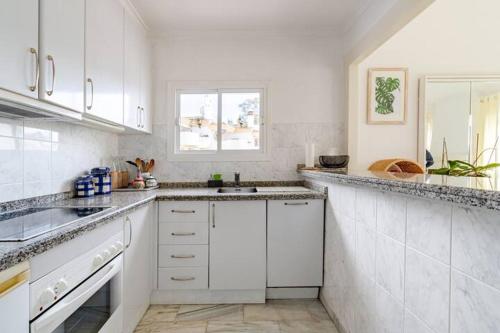 a white kitchen with white cabinets and a sink at Casa Tropicana Family & Golf in Sitio de Calahonda