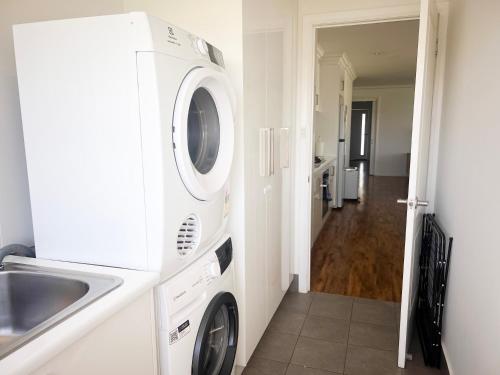 a kitchen with a washing machine and a sink at Darcy Drive in North Wagga