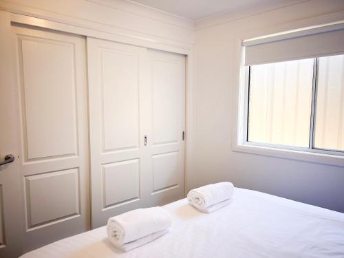a white bedroom with two towels on a bed at Darcy Drive in North Wagga