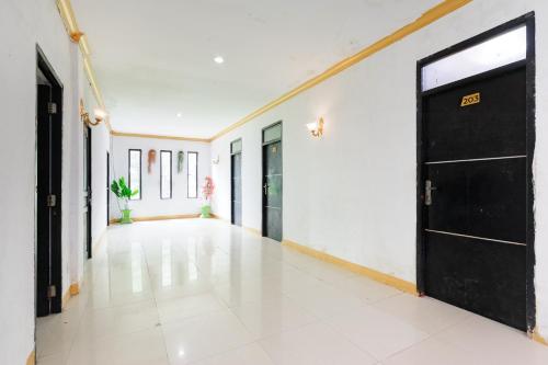 an empty hallway with a black door and white walls at RedDoorz Near RSUD Embung Fatimah Batam in Batam Center