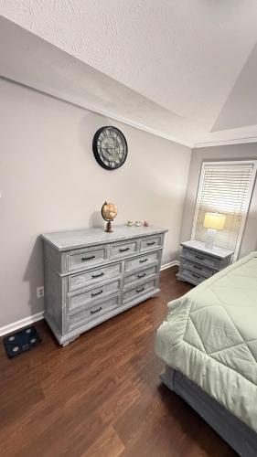 a bedroom with a dresser and a clock on the wall at Private Pool Paradise in Prattville