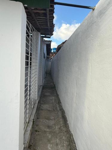 a narrow alley with a white wall next to a building at Casa Com Piscina em Itamaracá in Itamaracá