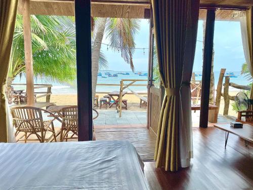 a bedroom with a bed and a view of the beach at TRÚ HOUSE in Mỹ Quang