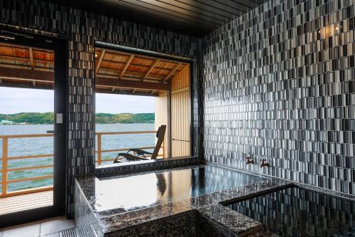a room with a tub with a view of the water at Sennentei in Yurihama
