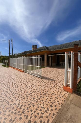a fence in front of a house with a building at Ouvir das Ondas - Xangri-lá in Xangri-lá