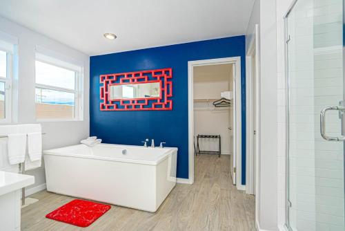 a bathroom with a white tub and a blue wall at Desert Picasso! Pool, Spa, Games, Mountain Views in Desert Hot Springs