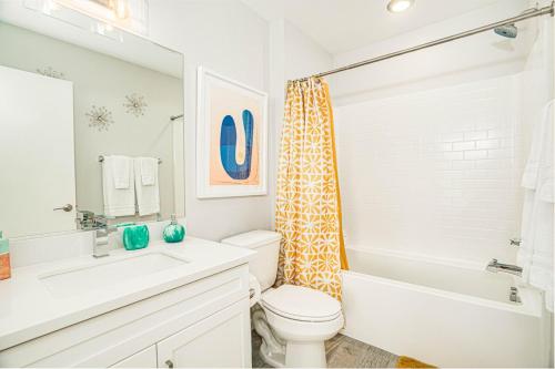 a white bathroom with a toilet and a tub and a sink at Desert Picasso! Pool, Spa, Games, Mountain Views in Desert Hot Springs