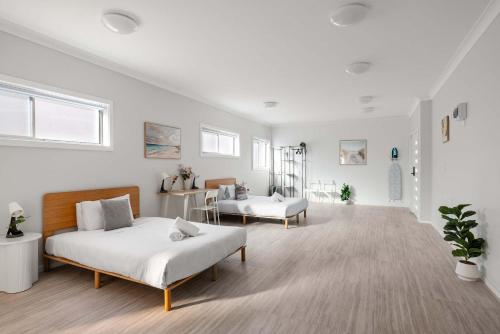 a white room with two beds and a chair at Comfort Stay - Detached Quadruple Studio Room with Simple Kitchenette near Top Ryde city in Sydney