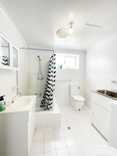 a white bathroom with a sink and a toilet at 2BR entire apartment beach in Glenelg