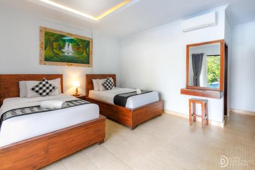 a bedroom with two beds and a mirror and a window at Tinggian Hill Retreat in Nusa Penida