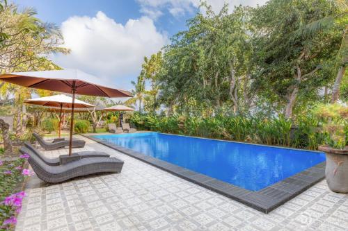 a swimming pool with two chairs and an umbrella at Tinggian Hill Retreat in Nusa Penida