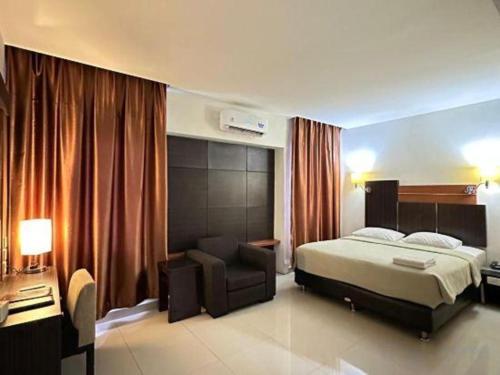 マナドにあるTravello Hotel Manadoのベッドと椅子のあるホテルの部屋