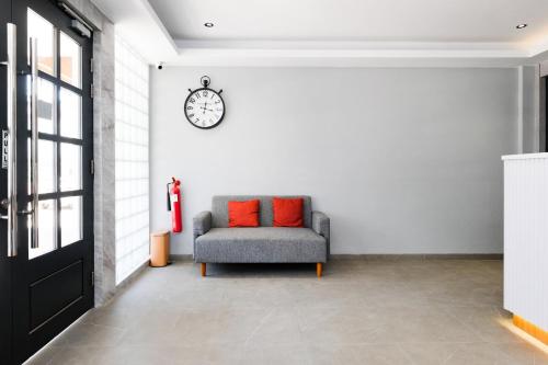 a room with a chair and a clock on the wall at Urbanview Tiana Residence Nagoya Batam by Reddoorz in Nagoya