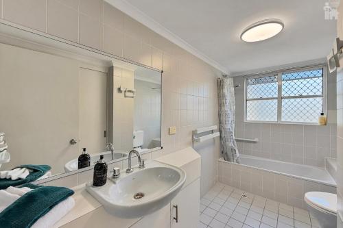a white bathroom with a sink and a tub at Villa Venezia Apt 3 - Spacious Hervey Bay esplanade apartment in Hervey Bay