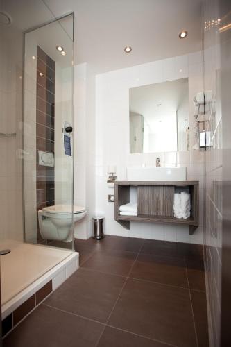 a bathroom with a sink and a toilet and a shower at WestCord City Centre Hotel in Amsterdam