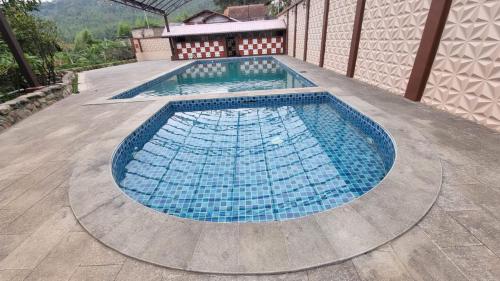 a large swimming pool with blue tiles on a deck at Qion's Villa in Cibogo