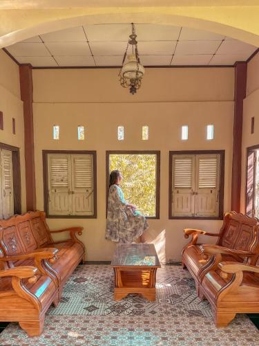 a woman standing in a living room looking out a window at Qion's Villa in Cibogo