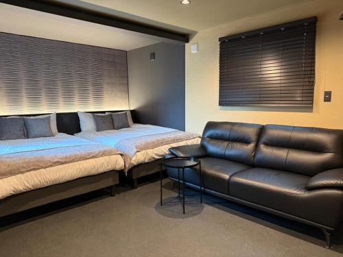 a bedroom with two beds and a leather couch at The Zen Residence Sapporo in Sapporo