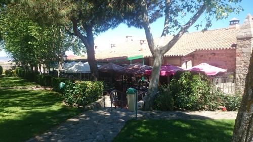 a patio with tables and umbrellas in a yard at Hotel Restaurante Sonsoles in Avila