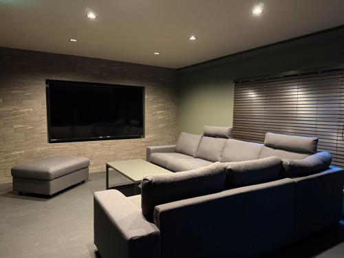 a living room with a couch and a flat screen tv at The Zen Residence Sapporo in Sapporo
