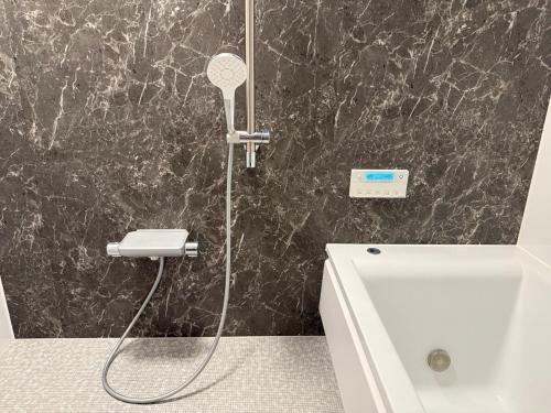 a bathroom with a shower with a shower head and a sink at The Zen Residence Sapporo in Sapporo