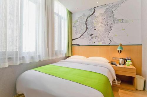 a bedroom with a bed with a green and white blanket at Vatica Hotel Hefei Yaohai Longgang Subway Station in Hefei