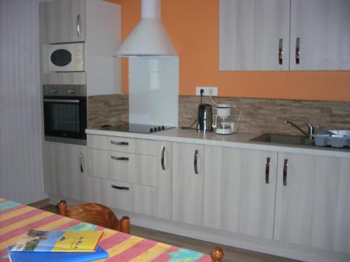 a kitchen with white cabinets and a sink at Gîtes Les Grandes Voies - Clé Vacances in Le Ménil