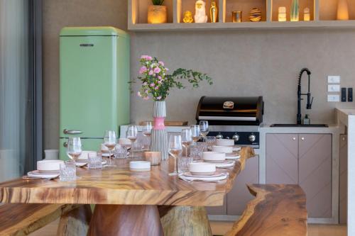 a table with glasses and a vase of flowers on it at Rosa Del Mar Seaview Villa with gym in Ban Nong Chaeng