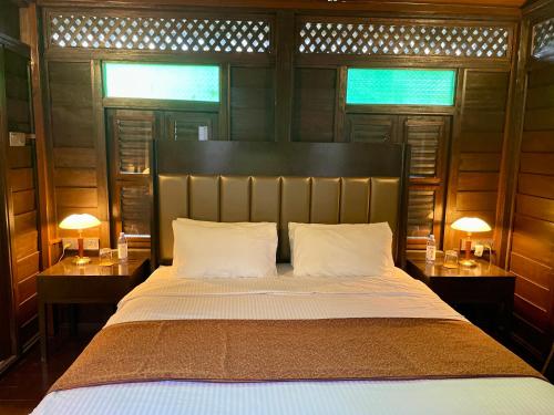 a bedroom with a bed with two tables and two lamps at Landmark Cenang in Pantai Cenang