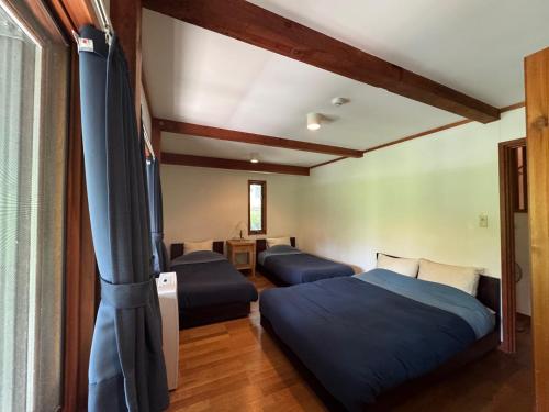 a bedroom with two beds and a flat screen tv at Cabin D 3min walk Lake Saiko remote work BBQ, 5min drive Kawaguchi Lake Mt Fuji view in Narusawa