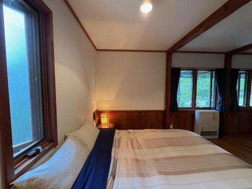 a bedroom with a bed and two windows at Cabin D 3min walk Lake Saiko remote work BBQ, 5min drive Kawaguchi Lake Mt Fuji view in Narusawa
