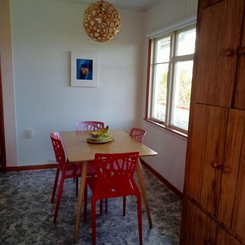 a dining room with a table and red chairs at Dated but Delightful on D'Arcy in Richmond