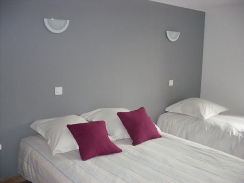 two beds in a bedroom with purple and white pillows at Gîtes Les Grandes Voies - Clé Vacances in Le Ménil