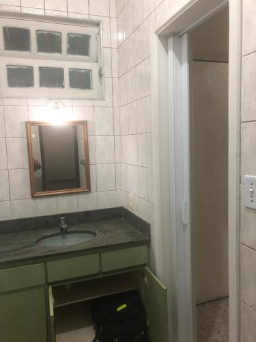 a bathroom with a sink and a mirror at Suites Pitangueiras in Guarujá