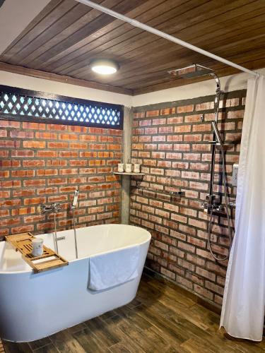 a bath tub in a bathroom with a brick wall at Landmark Cenang in Pantai Cenang
