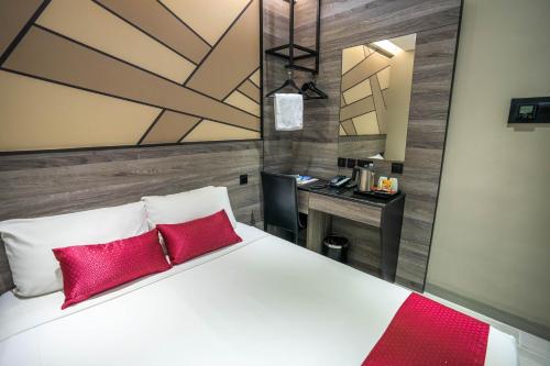 a bedroom with a bed with red pillows and a desk at Hotel 81 Orchid in Singapore