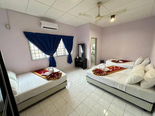 two beds in a room with blue curtains at Bentong Makmur 118 Homestay in Bentong