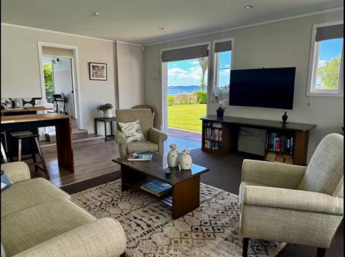 a living room with a flat screen tv and furniture at The Lake House with private spa Lake Rotorua in Rotorua