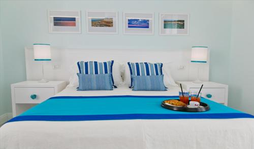 a white and blue bed with a tray of food on it at Terra d'Acqua Resort & SPA in Torre Mozza