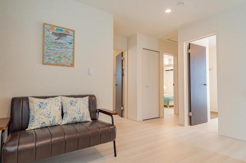 a living room with a leather couch and a painting on the wall at Tropical Beach Vacation House in Ginowan
