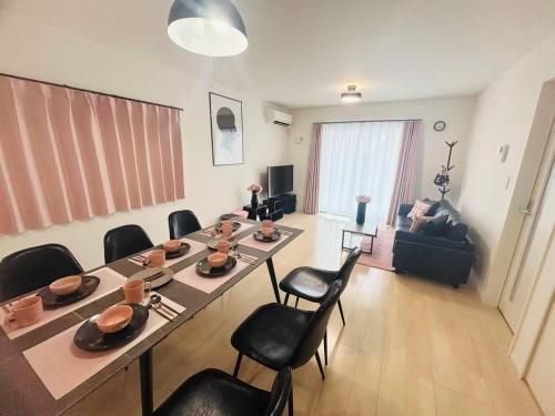 a living room with a long table and chairs at ZZOKIAI緋桜 Open in September 2025! 30-second walk to the sea!4LDK!Free parking! in Itoman