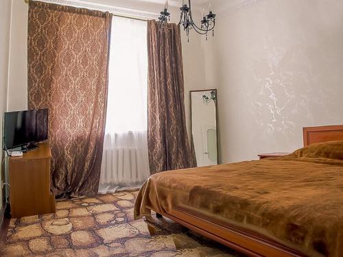 a bedroom with a bed and a tv and a window at Apartments on Sobornaya Street near the waterfront in Mykolaiv